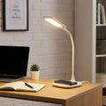 White LED desk lamp with a flexible neck and Qi charging base illuminates a workspace with a laptop and notebook.