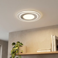 Modern circular recessed LED downlight with concentric nickel and glass rings installed on a white ceiling.