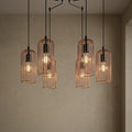 Eglo Roccamena six-light pendant featuring copper wire cages and black cables at staggered heights against a plain wall.