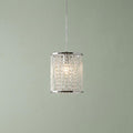 A chrome and crystal cylinder pendant light with glowing beads against a sage green wall.