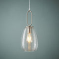 Nickel ceiling pendant with a clear ribbed glass shade and illuminated bulb against a muted teal wall.