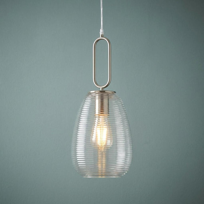 Nickel ceiling pendant with a clear ribbed glass shade and illuminated bulb against a muted teal wall.
