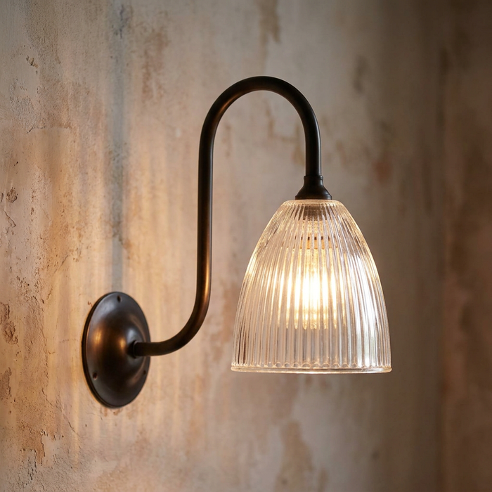 Elongated prismatic wall light with a bronze swan neck arm on a rustic textured wall.