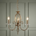 Elstead Aegean Aged Brass 3 Light Chandelier with crystal accents against a sage green paneled wall.