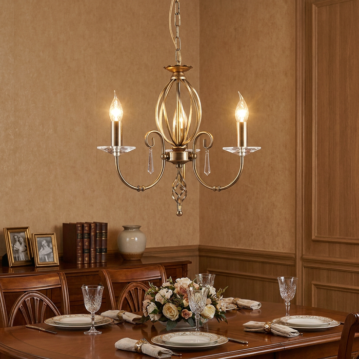 Aged brass 3-light chandelier with crystal accents hanging above a set dining table in a traditional room.