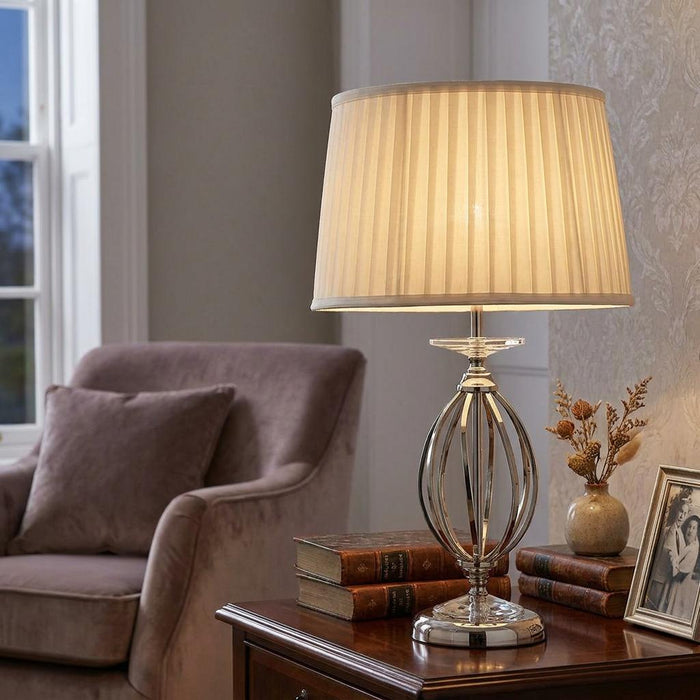 Elstead Aegean table lamp with polished nickel open base and pleated cream shade on a wooden side table.