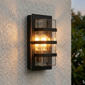 Contemporary Elstead Boden black outdoor wall light with clear panes and warm glowing bulbs on a textured wall.