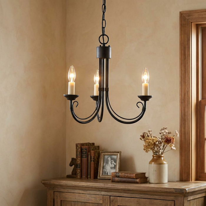 Elstead Chartwell three-light black chandelier with candle-style bulbs hanging above a wooden side table.