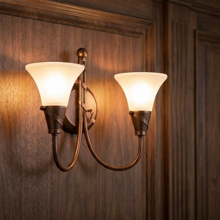Twin antique copper wall light with frosted glass shades, glowing on a dark wood-paneled wall.