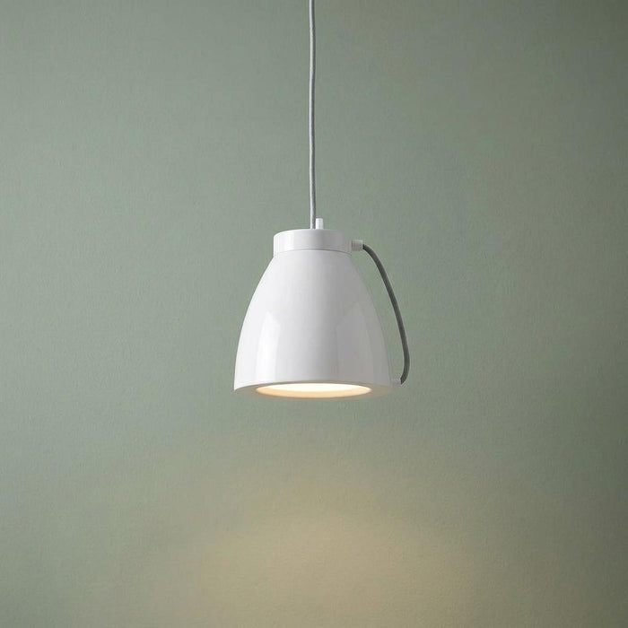 Modern white bell-shaped pendant light illuminated against a muted green background.