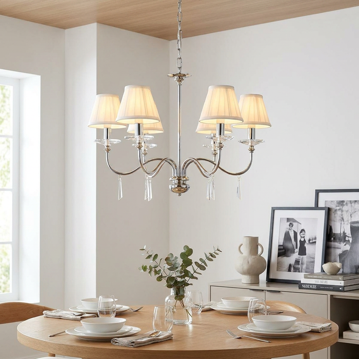 Elstead Finsbury Park 6-light polished nickel chandelier with cream shades hanging above a modern dining table.