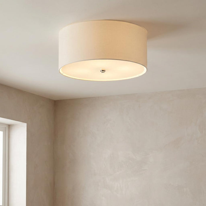 Cream fabric flush drum ceiling light with a polished chrome finial mounted on a neutral ceiling.