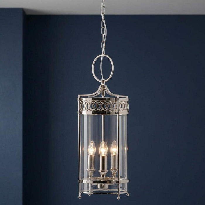 Elstead Guildhall polished nickel ceiling lantern with glass cylinder and three lights against a dark blue wall.