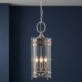 Elstead Guildhall polished nickel ceiling lantern with glass cylinder and three lights against a dark blue wall.
