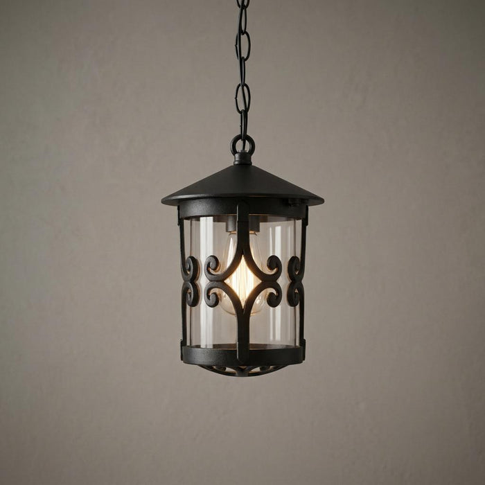 Black Elstead Hereford outdoor pendant lantern with decorative scrollwork and a lit bulb against a neutral wall.