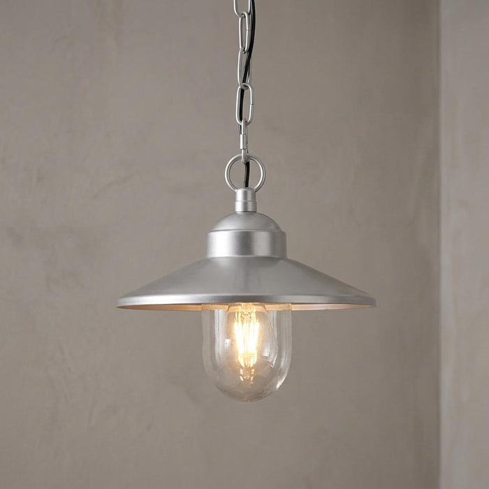 Elstead Klampenborg silver outdoor pendant light with a metal shade and glass-enclosed lit bulb against a neutral wall.