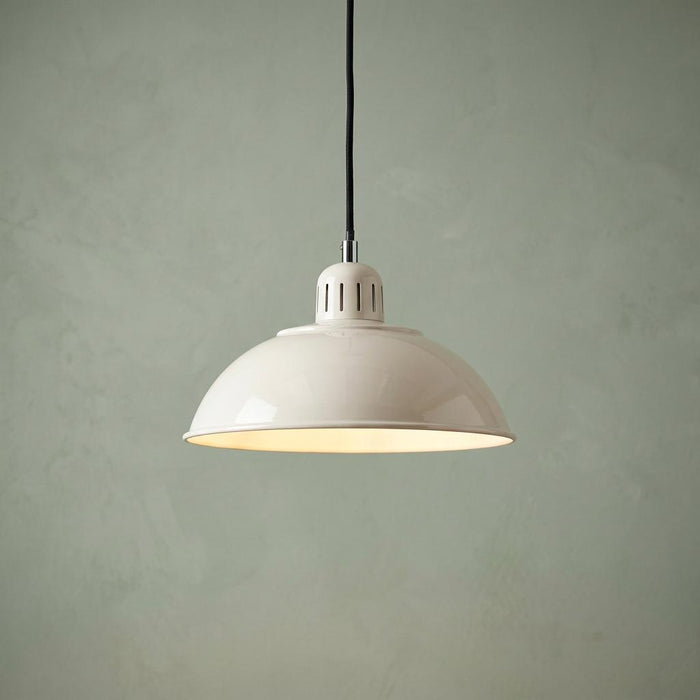 A cream dome-shaded pendant light with a black cord hanging against a pale green textured wall.