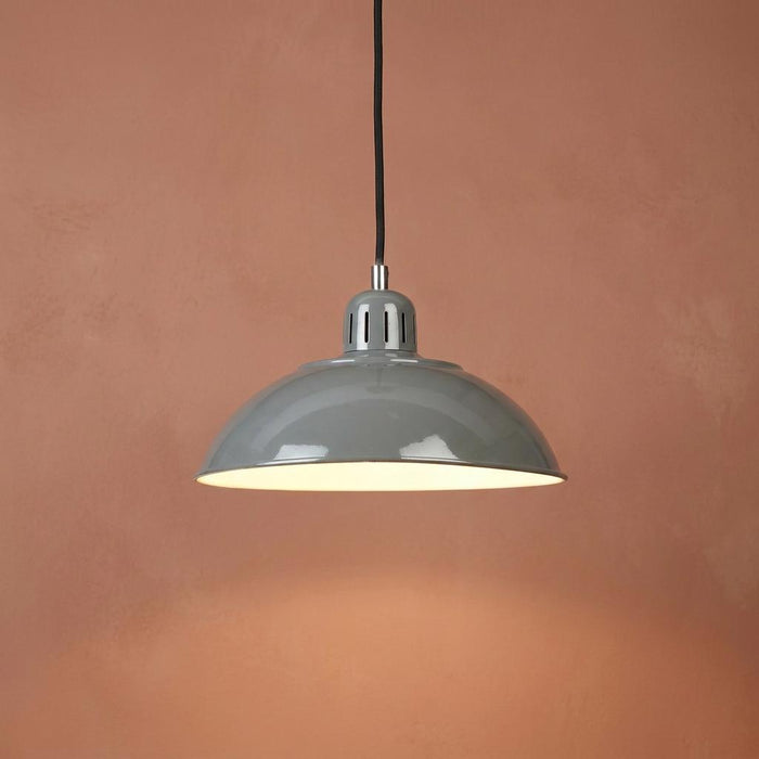 Grey industrial-style dome pendant light with a white interior glowing against a textured terracotta wall.