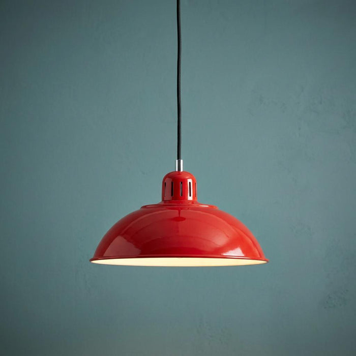 A vibrant red dome-shaped pendant light with a black cord hanging against a textured blue wall.