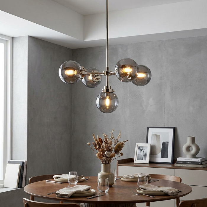 Elstead Lighting Kula 5-light polished nickel chandelier with smoke glass globes over a modern dining table.
