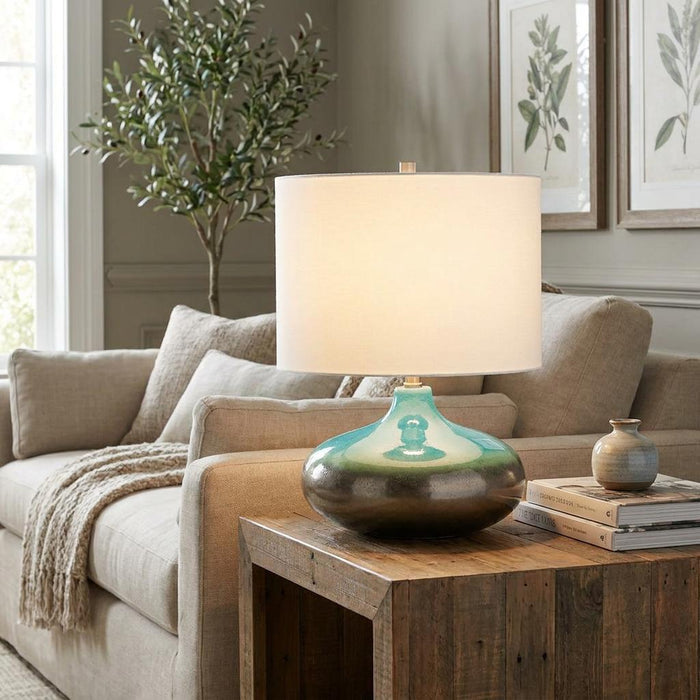 Small Laguna ceramic table lamp with a teal and bronze gradient base on a rustic wooden side table.