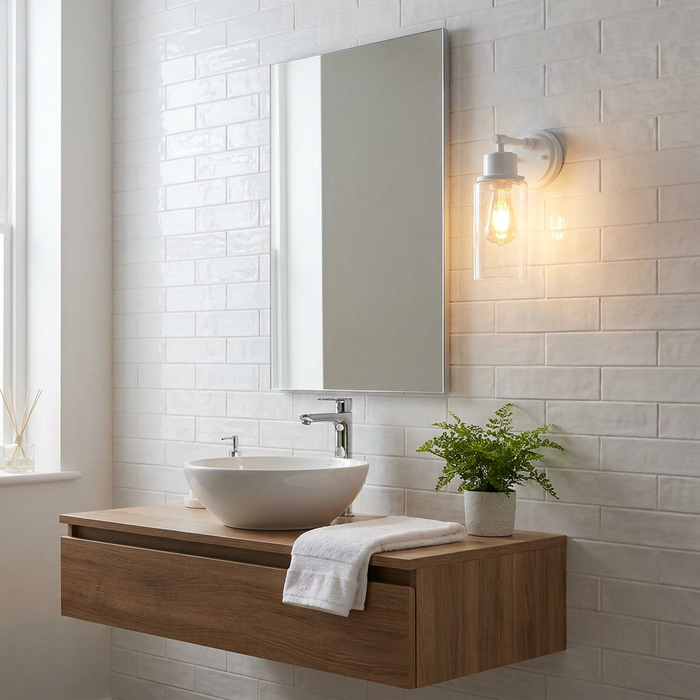 White wall light with a seeded glass shade illuminating a modern bathroom vanity against a white tiled wall.