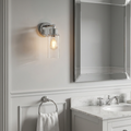 Polished chrome wall light with a seeded glass shade and Edison bulb, mounted in a classic bathroom setting.