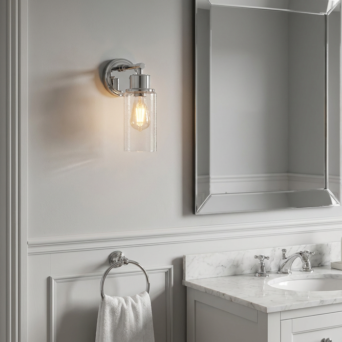 Polished chrome wall light with a seeded glass shade and Edison bulb, mounted in a classic bathroom setting.