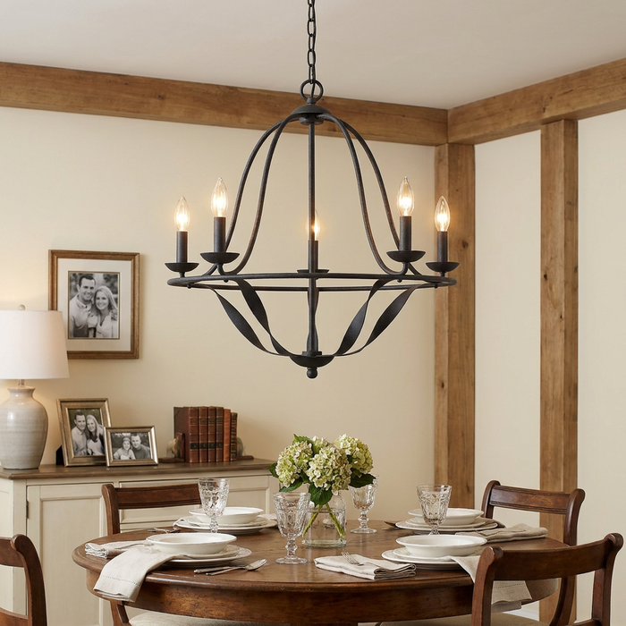 Grey five-light metal chandelier with curved arms hanging over a wooden dining table in a rustic dining room.