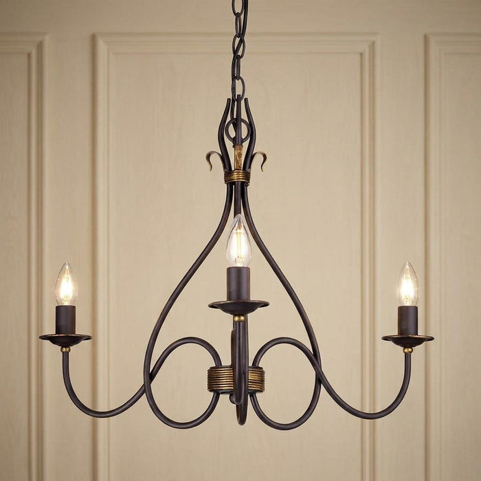 Traditional three-light rust and gold chandelier with elegant curved metalwork and lit candle bulbs.