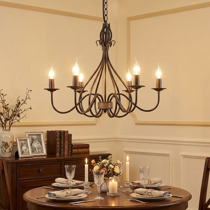 A six-light rust and gold chandelier illuminates a formal dining table set for a meal.