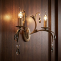 Elstead Lily 2-light bronze wall sconce with leaf design and crystal droplets on a wood panel.