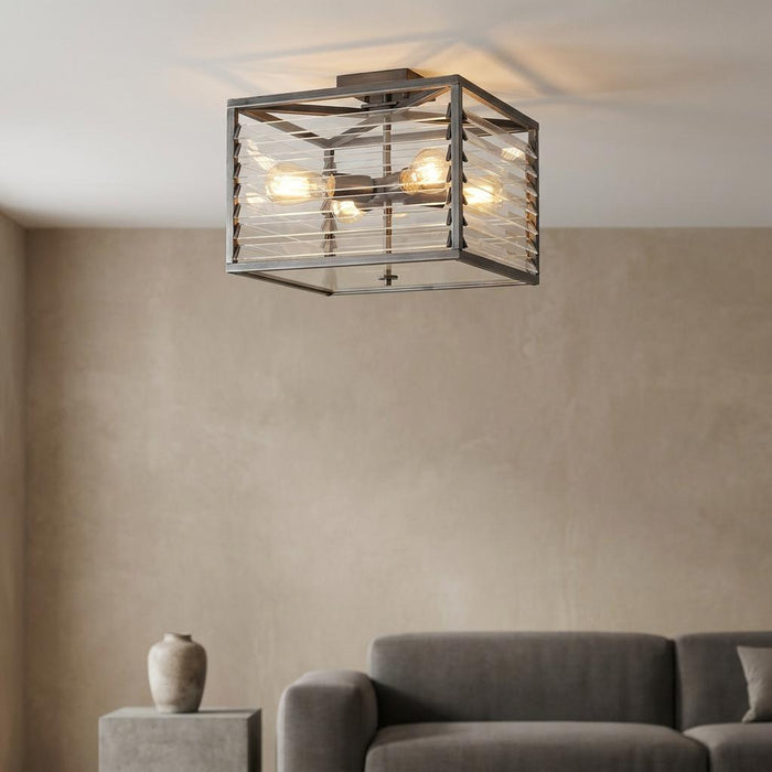 Gunmetal square ceiling light with glass louvres and four glowing bulbs in a minimalist living room.