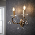 Elstead Lunetta bronze 2-light wall sconce with crystal droplets on dark damask wallpaper.
