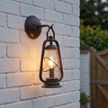Elstead Miners old bronze lantern-style outdoor light glowing on a white brick wall.