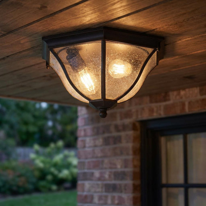 Traditional bronze flush-mount outdoor ceiling light with seeded glass, mounted on a wooden porch ceiling.
