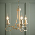 Ivory and gold three-light chandelier with decorative leaf accents hanging against a sage green paneled wall.