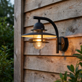 Black Elstead Oslo outdoor wall light with layered shades mounted on a rustic wooden wall and illuminated.