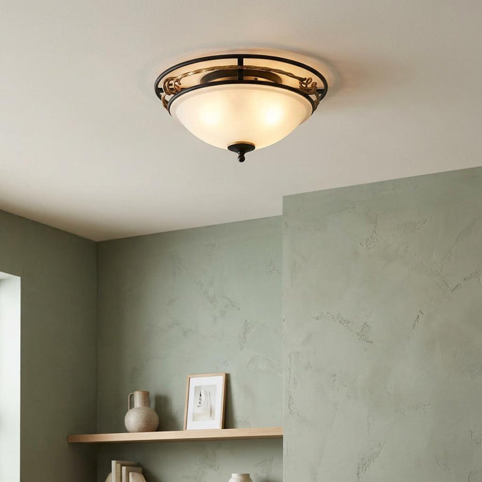 Black and gold flush dome ceiling light with frosted glass, mounted in a modern green-walled interior.