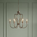 Elstead Pimlico 6-light dark bronze chandelier with elegant curved arms and crystal accents against a green wall.