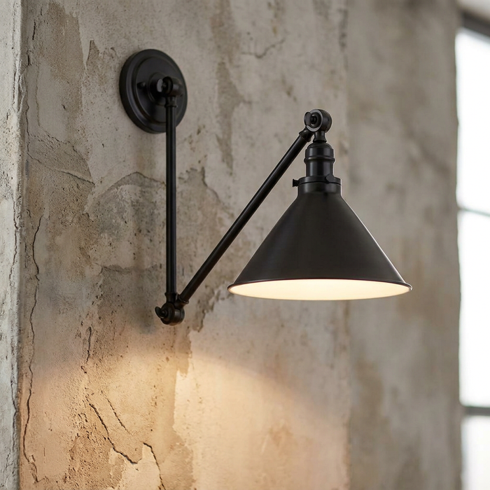 Old bronze industrial swing arm wall light with a conical shade mounted on a textured stone wall.