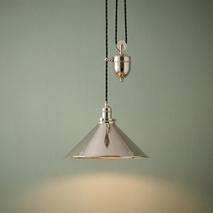 Polished nickel rise and fall pendant light with a conical shade and pulley mechanism against a sage green wall.