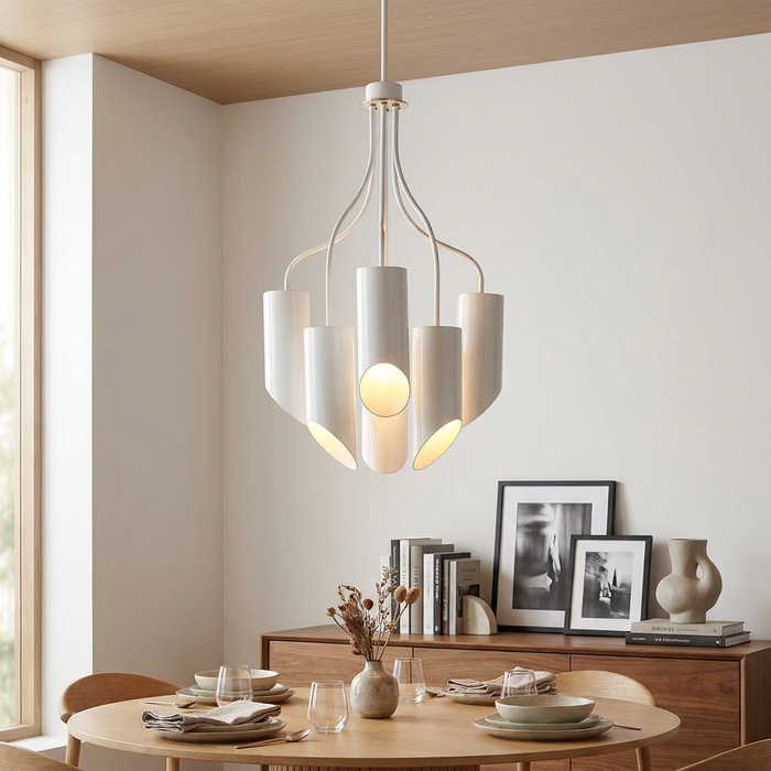 Modern white six-light chandelier with cylindrical shades hanging over a wooden dining table in a bright room.