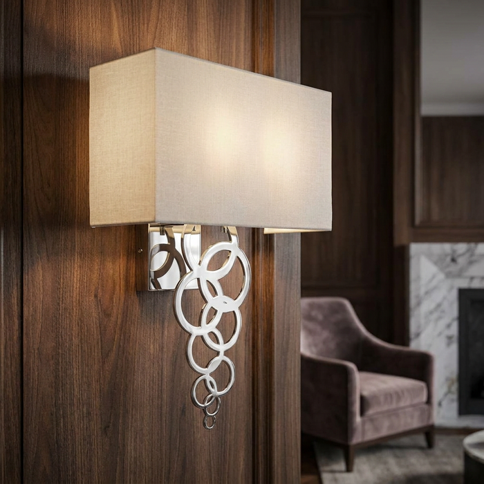 Polished chrome wall light with interlocking circles and a beige rectangular shade on a dark wood wall.