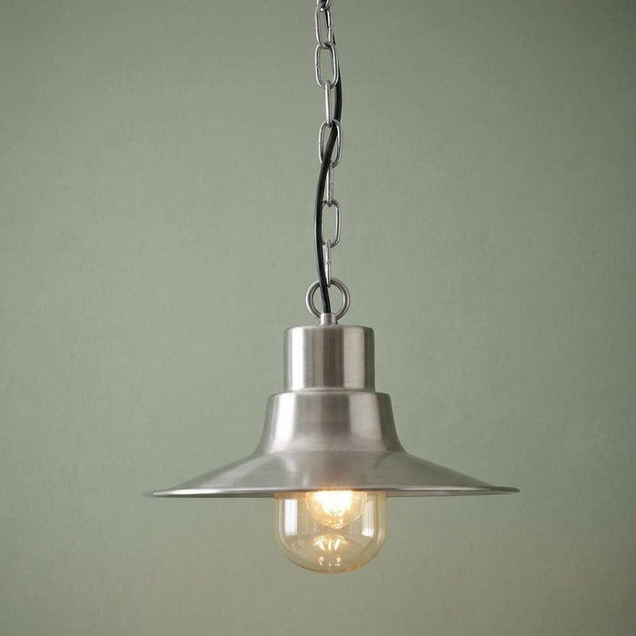 Antique nickel outdoor pendant light with a tiered metal shade and clear glass globe against a green background.