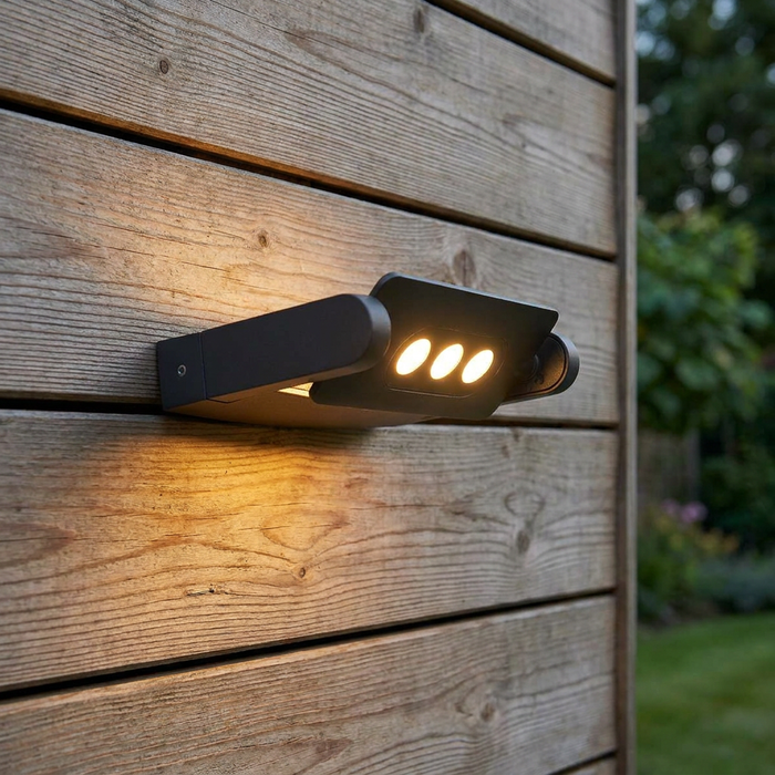 Modern graphite outdoor wall light with three warm LEDs mounted on a horizontal wooden plank wall.
