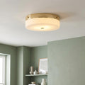 Gold flush-mount bathroom ceiling light with white opal glass diffuser, installed in a sage green room.