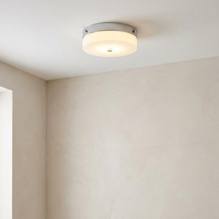 Circular flush mount bathroom light with polished chrome trim and frosted glass diffuser on a white ceiling.