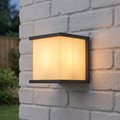 Modern square graphite outdoor wall light with a warm glow mounted on a white brick wall.