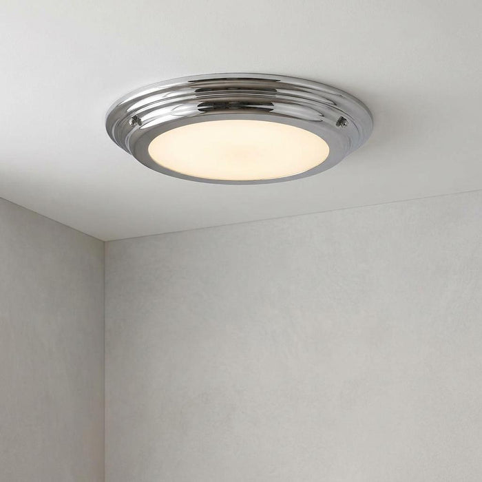 Circular flush-mounted bathroom ceiling light with a polished chrome trim and glowing frosted diffuser.